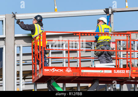 Männliche Arbeitnehmer in einem industriellen Skyjack Cherry Picker arbeitet auf einer Baustelle in Großbritannien. Stockfoto