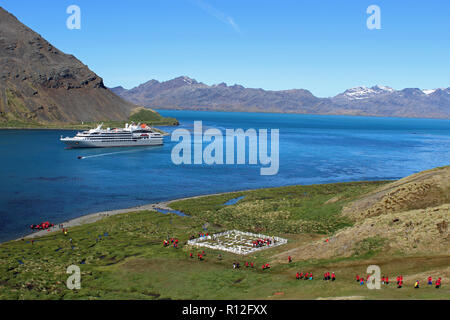 Grytviken, King Edward Cove Harbour, South Georgia, South Atlantic. Kreuzfahrtschiff Passagiere zu Fuß vom Friedhof, wo Ernest Shackleton begraben ist Stockfoto