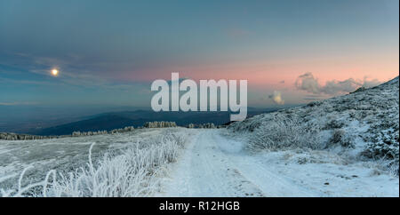 Sonnenuntergang auf einer Bergspitze - gefrorene Landschaft, lebhafte Farben, kalten Abend - Schneebedeckte Bäume unter sanften Mondlicht Stockfoto