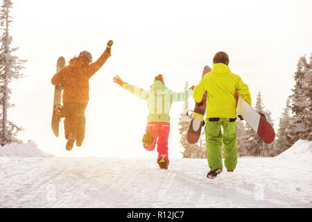 Sind eine Gruppe von drei glückliche Freunde snowboarder Spaß und läuft Hang mit Snowboards, Ski Stockfoto