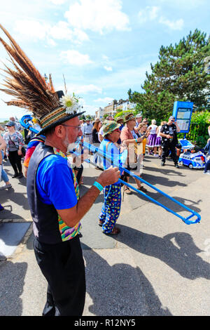 Broadstairs Folk Woche Festival. Ältere männliche tragen Hut mit Federn, Folk Musiker, stehend im Freien mit anderen, während der Wiedergabe eines blauen Posaune. Stockfoto