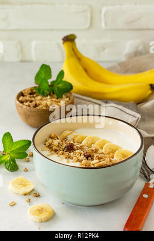 Müsli. Müsli mit Joghurt, Schokolade und Banane auf einem weißen Tisch aus Stein. Das Konzept der gesunden Ernährung und Diät. Stockfoto