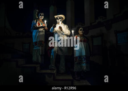 Merida, Cementerio General, Mexiko - 31. Oktober 2018: Customed Mann mit Kerzen und zeigen und zwei Frau gekleidet wie Catrinas mit Totenkopf Make-up posi Stockfoto