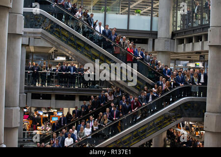 London, Großbritannien. 9. Nov 2018. Tausende Linie das Atrium und Fahrtreppen bei Lloyd's Gedenkstunde. Poppy Blütenblätter fallen von oben in die atriium als das Horn spielt "Die letzten Post". Die lutine Bell Sounds während der kranzniederlegung mit Würdenträgern einschließlich der Oberbürgermeister von London und Chelsea Rentner mit den 7 Gewehre, die den Schutz der Ehre Credit: Tommy London/Alamy leben Nachrichten Stockfoto