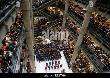 London, Großbritannien. 9. Nov 2018. Tausende Linie das Atrium und Fahrtreppen bei Lloyd's Gedenkstunde. Poppy Blütenblätter fallen von oben in die atriium als das Horn spielt "Die letzten Post". Die lutine Bell Sounds während der kranzniederlegung mit Würdenträgern einschließlich der Oberbürgermeister von London und Chelsea Rentner mit den 7 Gewehre, die den Schutz der Ehre Credit: Tommy London/Alamy leben Nachrichten Stockfoto