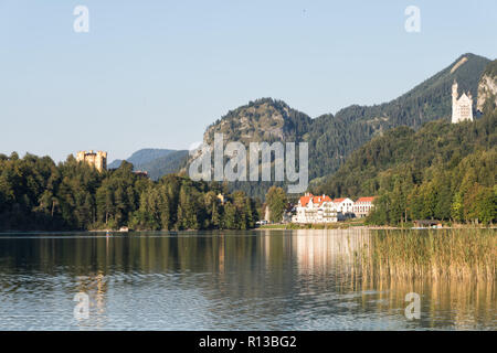 Alpsee mit Hohenschwangau, Neuschwanstein und Restaurant Alpenrose am See an einem warmen sonnigen Abend Ende September. Schwangau, Füssen, Bayern Stockfoto