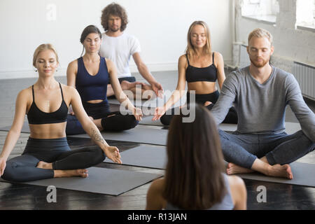 Gruppe von sportlichen Menschen in Lotus Übung mit weiblichen Kursleiter Stockfoto