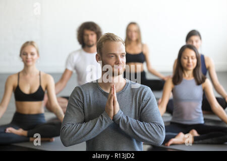 Gruppe von sportlichen Menschen in Lotus Übung mit männlichen Instructor Stockfoto
