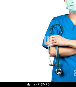 Chirurg Arzt tragen blaue scrubs Shirt einheitliche und grünen Gesichtsmaske. Arzt stand mit verschränkten Armen und Hand Stethoskop. Healthcare professi Stockfoto