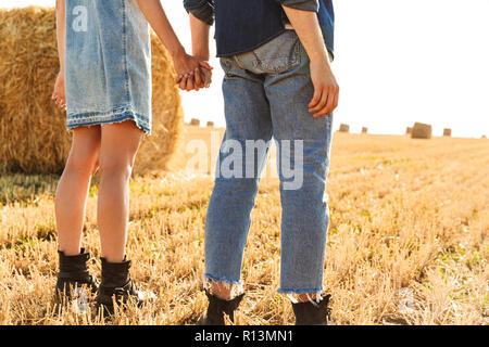 Zurück 7/8-Anzeigen Bild eines jungen Paares stehen gemeinsam auf dem Weizenfeld, halten sich an den Händen Stockfoto