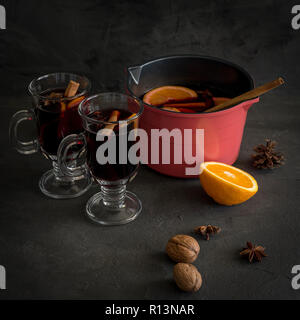 Wein im Glas Glühwein, Pan mit Wein, Orange, Nussbaum und Gewürze in der Nähe von auf schwarzem Hintergrund Stockfoto