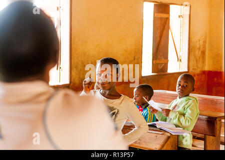 Bafoussam Kamerun - 06. August 2018: lächelnde Mädchen während der Lektion in der Dorfschule im Gespräch mit Lehrer Stockfoto