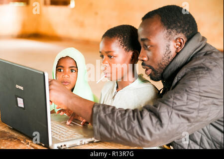 Bafoussam Kamerun - 06. August 2018: Junge afrikanische Kinder lernen Computer mit jungen Lehrer berühren Bildschirm zu verwenden Stockfoto