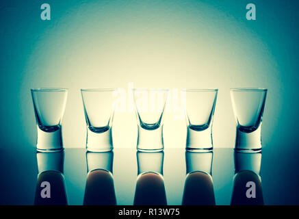 Kleine Gläser mit einem Drink Shots von Alkohol stainding in einer Tabelle mit Reflektion Stockfoto