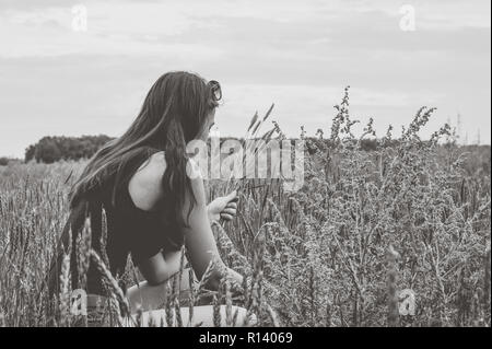 Das Mädchen Weizenernte ährchen auf dem Feld. Die Schwarz-Weiß-Fotografie. Stockfoto