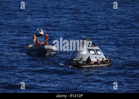 Das Team der NASA und der US-Marine Taucher sicher ein mock up Version des Orion Next Generation Space Capsule wie Sie es vorbereiten, in dem Deck der USS John S. Murtha während einer offenen Ozean recovery test Oktober 31, 2018 im Pazifischen Ozean zu bringen. Die NASA und die US-Marine hat nicht ausgeführt, offenen Ozean der Wiederherstellung eines bemannten Raumkapsel seit der Apollo Projekt in den 60er Jahren und sind den Prüfverfahren und -Hardware, der verwendet werden soll, um das Raumfahrzeug Orion wiederherzustellen, nachdem es den in den Pazifischen Ozean Spritzer folgende künftige interplanetare Raumfahrt Missionen. Stockfoto