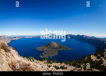 Blick auf den Kratersee und Wizard Island von der Wächter Turm Aussichtspunkt auf einem sonnigen, wolkenlosen Herbst Tag mit nur einem leichten Hauch von Rauch in den Horizont f Stockfoto