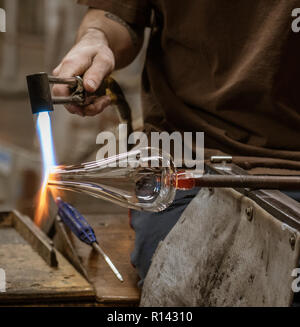 Eine Glasbläserei artist Formen ein Blob Glas in ein Gefäß mit einem Gasbrenner in Vermont. Stockfoto