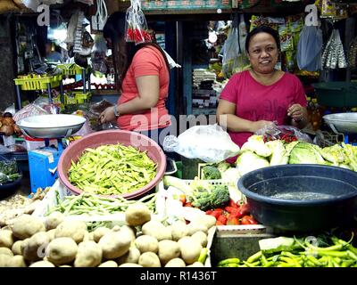 BINANGONAN, Rizal, Philippinen - 8. NOVEMBER 2018: eine Obst- und Gemüse Anbieter verkauft frische Produkte auf einem öffentlichen Markt. Stockfoto