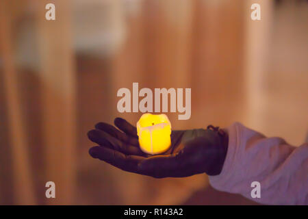 Weibliche Hand in schwarz Handschuh Holding eine künstliche Kerze Stockfoto