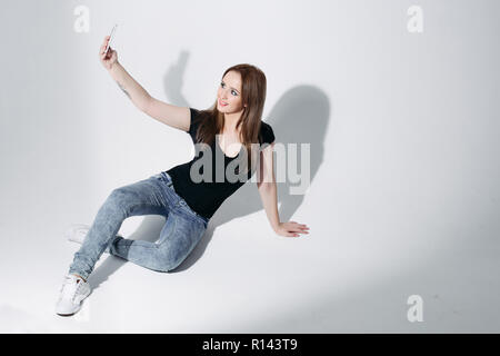 Hübsches Mädchen in schwarzen T-Shirt und Jeans, selfie auf Sitzung Stockfoto