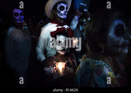 Merida, Cementerio General, Mexiko - 31. Oktober 2018: Customed Teilnehmer der Parade mit Totenkopf Make-up, mit einem Cowboy Mann und Kind mit Blumen Stockfoto