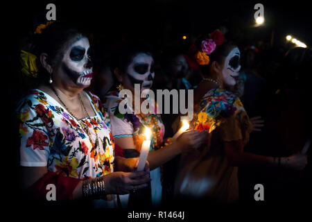 Merida, Cementerio General, Mexiko - 31. Oktober 2018: Drei customed Frau gekleidet wie Catrinas mit Totenkopf Make-up Probleme mit der Kerzen bet Stockfoto