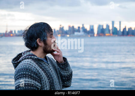 Ein junger Mann rauchen eine gemeinsame mit der Innenstadt von Vancouver, BC, im Hintergrund kurz nach Kanadische Marihuana Legalisierung. Stockfoto