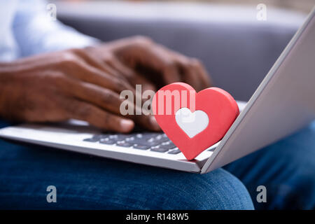 Nahaufnahme von roten Heartshape auf der Tastatur während des Menschen Hand mit Laptop Stockfoto