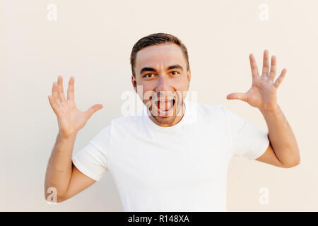 Schreien, Hass, Wut. Weinend emotionale wütenden Mann schreiend auf Orange Studio Hintergrund. Emotionale, junges Gesicht. männliche Brustbild. Stockfoto