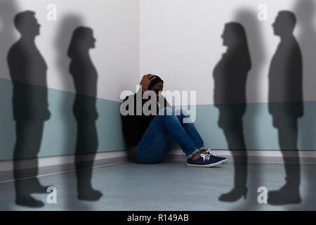 Die Schatten von Menschen, die in der Nähe von Angst Mann sitzt auf dem Boden Stockfoto