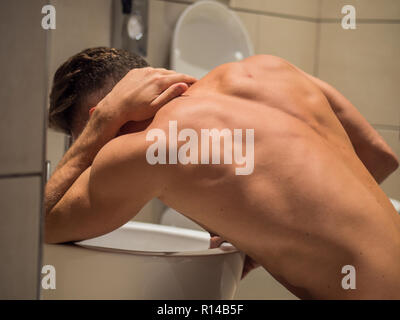 Betrunkene junge Mann erbrechen in der Toilette zu Hause Stockfoto