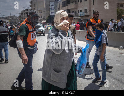 Eine Frau gesehen, die ihr Gesicht nach dem Einatmen Gas durch die israelische Armee während der Demonstration feuerte Tränengas. Wie die US-Regierung verschiebt die Botschaft nach Jerusalem, Tausende von Palästinensern protestieren im Gaza-Streifen und im Westjordanland noch am gleichen Tag, markiert den 70. Jahrestag der Nakba. Im Gazastreifen, israelische Truppen erschossen mehr als 58 Menschen verletzt und 2.000 an diesem Tag. Bei militärischen Qalandiya checkpoint Hunderte marschierten und warfen Steine auf israelische Soldaten, die mit scharfer Munition schießen, Gummi bullet reagiert und auch Tränengas. Stockfoto