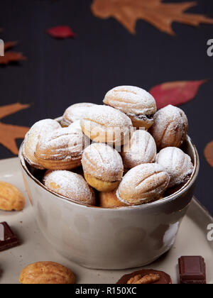 Walnuss geformte Plätzchen auf einer Platte, mit Spitzen der Schokolade, herzförmige Würfelzucker und Walnüsse. Russische oreshki. Stockfoto
