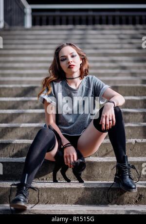 Schöne Rock Mädchen und kleine schwarze Kätzchen auf einer Treppe Stockfoto