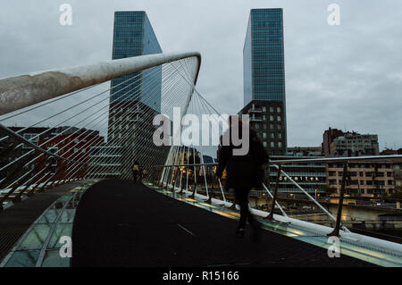 Ansicht eines Zubizuri Brücke über den Fluss Nervion, mit Fußgängern zu Fuß auf dem Weg zu ihren Arbeitsplätzen in eine Wolke, Tag, zwischen den Türmen von Bilbao, Vi Stockfoto