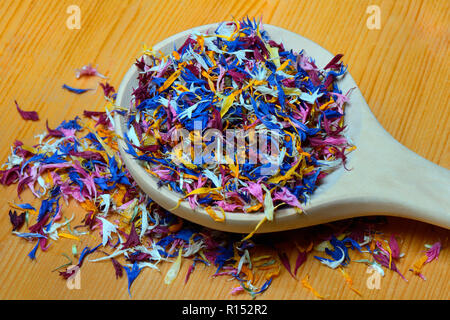 Bluetenblaetter in Holzloeffel, essbare Blueten, Centaurea cyanus, Calendula officinalis, Helianthus annuus Stockfoto