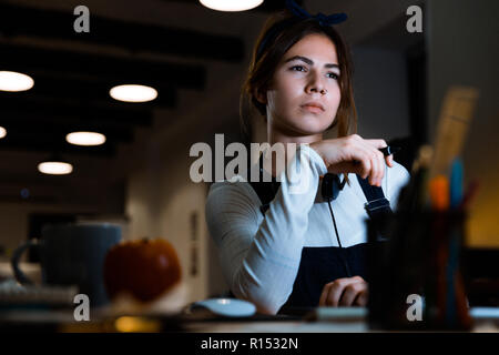 Bild von Konzentriertem junge Frau Designer im Büro die Arbeit mit Tablet-PC und Computer in der Nacht. Stockfoto
