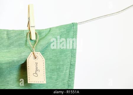 Organische Kleidung. Grüne t-shirt hängen an einer Wäscheleine. Weißer Hintergrund. Kopieren Sie Platz. Stockfoto