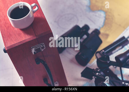 Hintergrund mit Tasse Kaffee und verschwommenes Fernglas, Bleistift, marine Sextant auf Navigationskarte liegen. Stockfoto