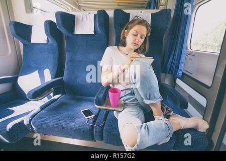 Stilvolle teenage Mädchen wird mit dem Zug. Zeichnet und hört Musik Stockfoto