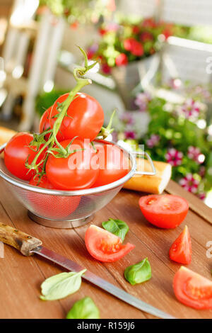 Frische Tomaten in einem küchensieb liegen auf einem Holz- fach Stockfoto