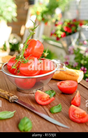 Frische Tomaten in einem küchensieb liegen auf einem Holz- fach Stockfoto