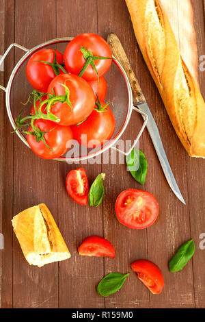 Frische Tomaten in einem küchensieb liegen auf einem Holz- fach Stockfoto