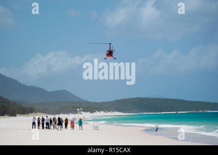 Hubschrauberlandeplatz am Whitehaven Beach, Whitsunday Islands, Queensland, Australien mit blauer Himmel, weißer Sand, blaues Meer und wartende Menschen Stockfoto