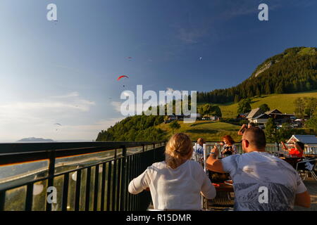 Anzeigen von Gleitschirmen fliegen in der späten Nachmittagssonne aus einem der Restaurants Col de La Forclaz über den See von Annecy Frankreich Stockfoto