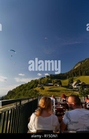 Anzeigen von Gleitschirmen fliegen in der späten Nachmittagssonne aus einem der Restaurants Col de La Forclaz über den See von Annecy Frankreich Stockfoto