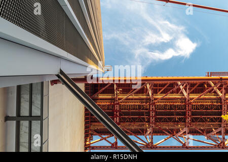 Der Blick von unten auf einer Säule in das rote Metall Brücke in Portugal unter dem blauen Himmel Stockfoto