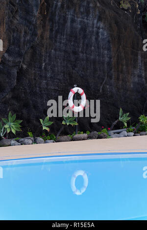 Leben Boje hängen an dunklen felsige Wand am Pool. Portugiesische Insel Madeira Stockfoto