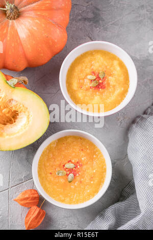 Ernährung Vegetarische Kürbis Suppe, auf einem grauen Hintergrund Textur und hellen orange Kürbis. Close-up. Stockfoto